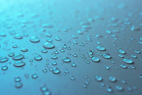 Many different drops of water rain on a blue background, close up