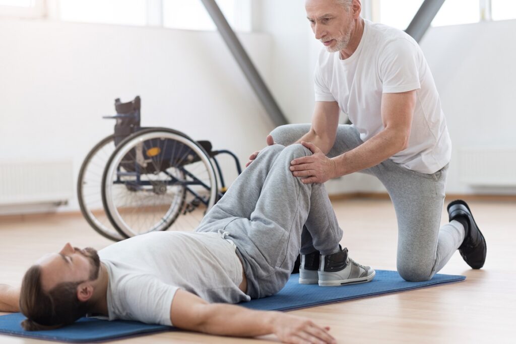 Skilled,Aged,Orthopedist,Stretching,The,Disabled,Person,In,The,Gym