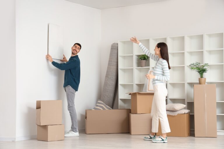 Young,Couple,Hanging,Painting,On,Wall,In,Room,On,Moving