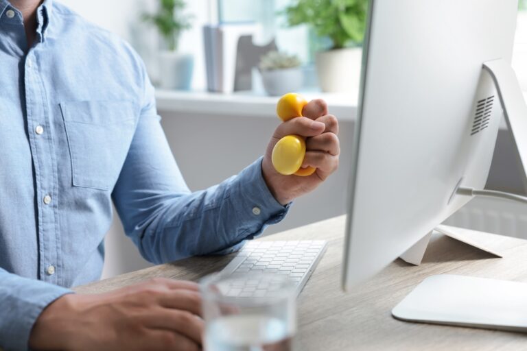 Man,Squeezing,Antistress,Ball,While,Working,With,Computer,In,Office,