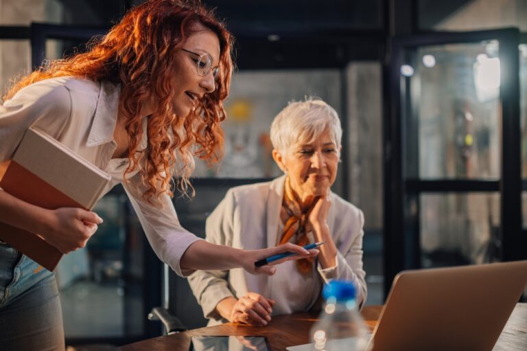 A,Young,Businesswoman,Standing,At,Modern,Workplace,And,Discussing,Digital