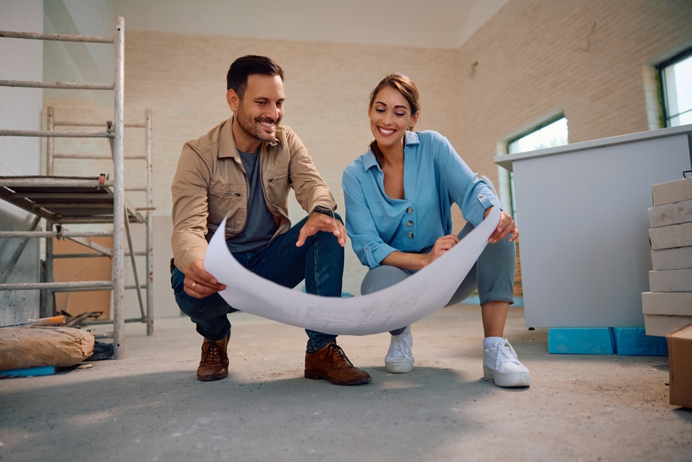 Happy,Couple,Going,Through,Housing,Plans,At,Their,Renovating,Home.