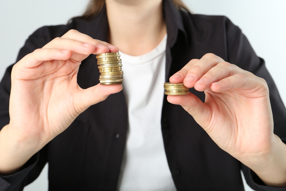 Financial,Inequality.,Woman,Comparing,Two,Stacks,Of,Coins,On,White