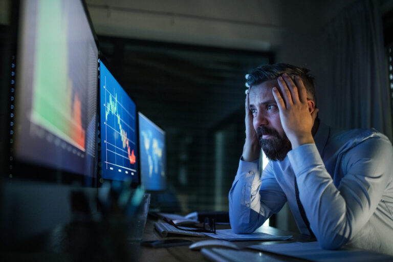 Frustrated,Businessman,With,Computer,Sitting,At,Desk,,Working,Late.,Financial