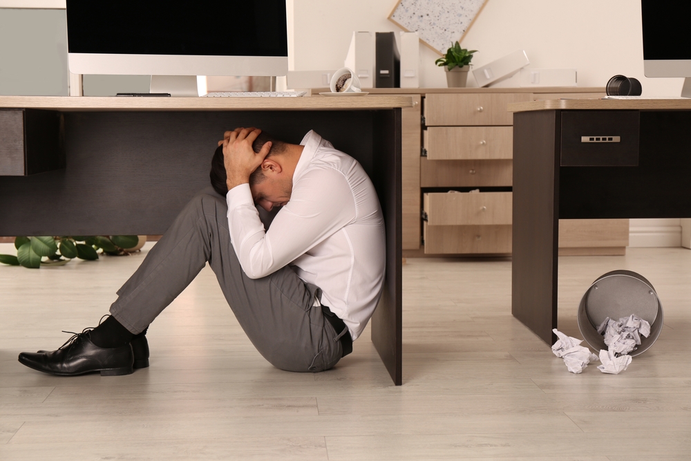 Scared,Man,Hiding,Under,Office,Desk,During,Earthquake